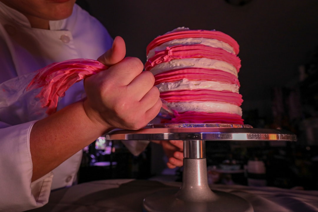 Pâtissière en train de décorer un layer cake à la poche à douille
